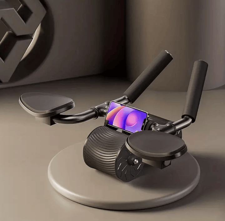 Schwarzes Bauchmuskelrad mit Griffen und Smartphone-Halterung auf grauem Hintergrund.