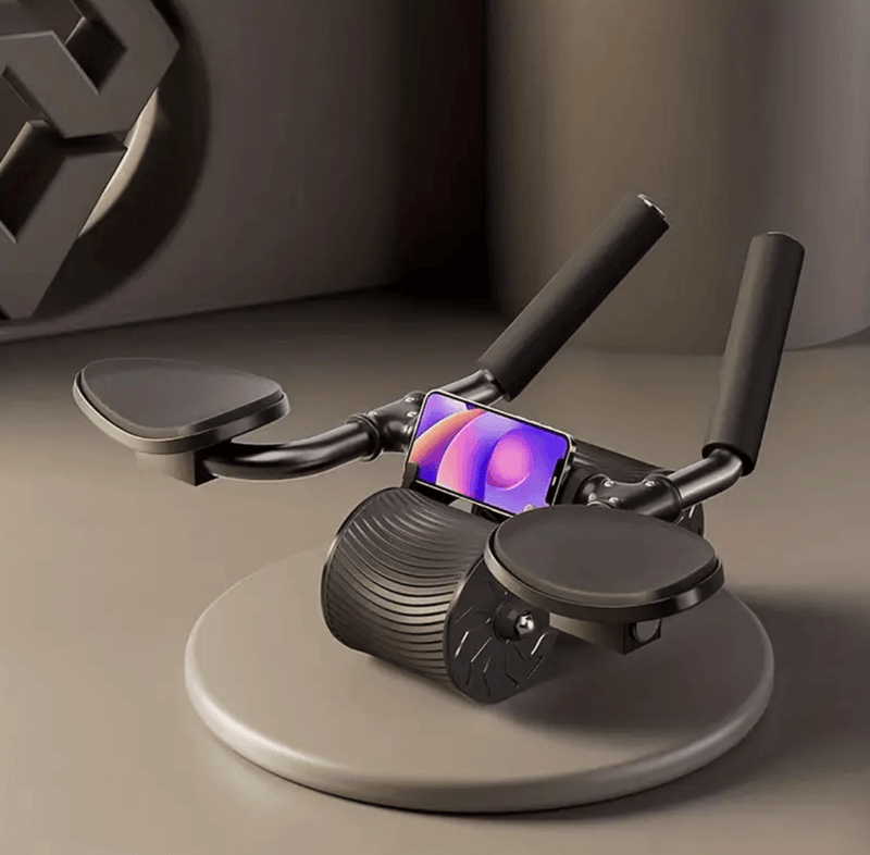 Schwarzes Bauchmuskelrad mit Griffen und Smartphone-Halterung auf grauem Hintergrund.