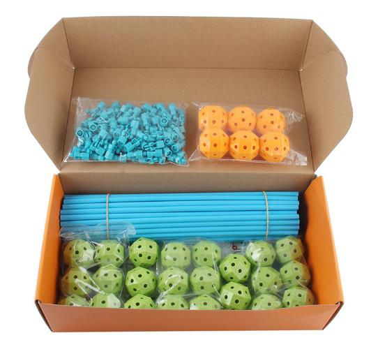 Baukasten-Set mit blauen Stäben, grünen und orange Kugeln in offener Kartonverpackung.