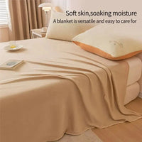 Beiges Bett mit weicher Decke, Kissen und Nachttischlampe im Schlafzimmer, gemütliche Einrichtung.