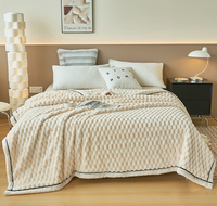 Beige Bettdecke aus Baumwolle auf modernem Bett mit Kissen, Nachttisch und Lampe im Schlafzimmer.