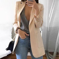 Frau in beigem Blazer, grauem Top und blauer Jeans, Spiegel-Selfie, modisch, elegant.