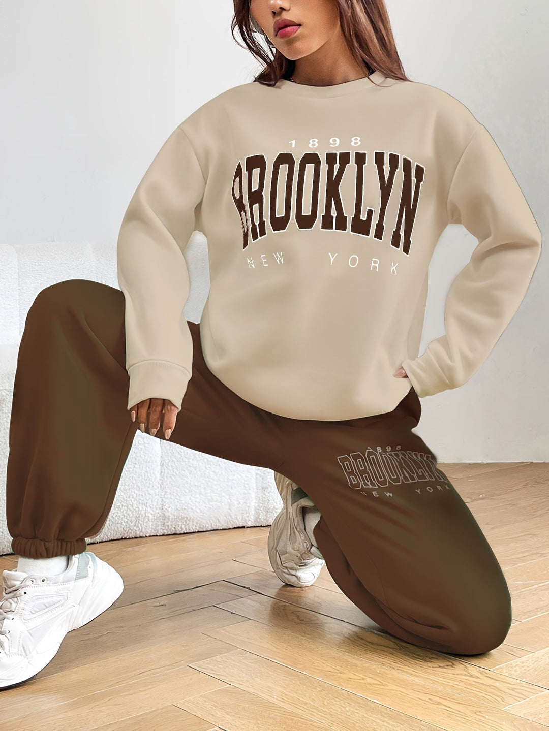 Frau in beigem Brooklyn-Sweatshirt und brauner Jogginghose, lässige Mode, Streetwear-Look.