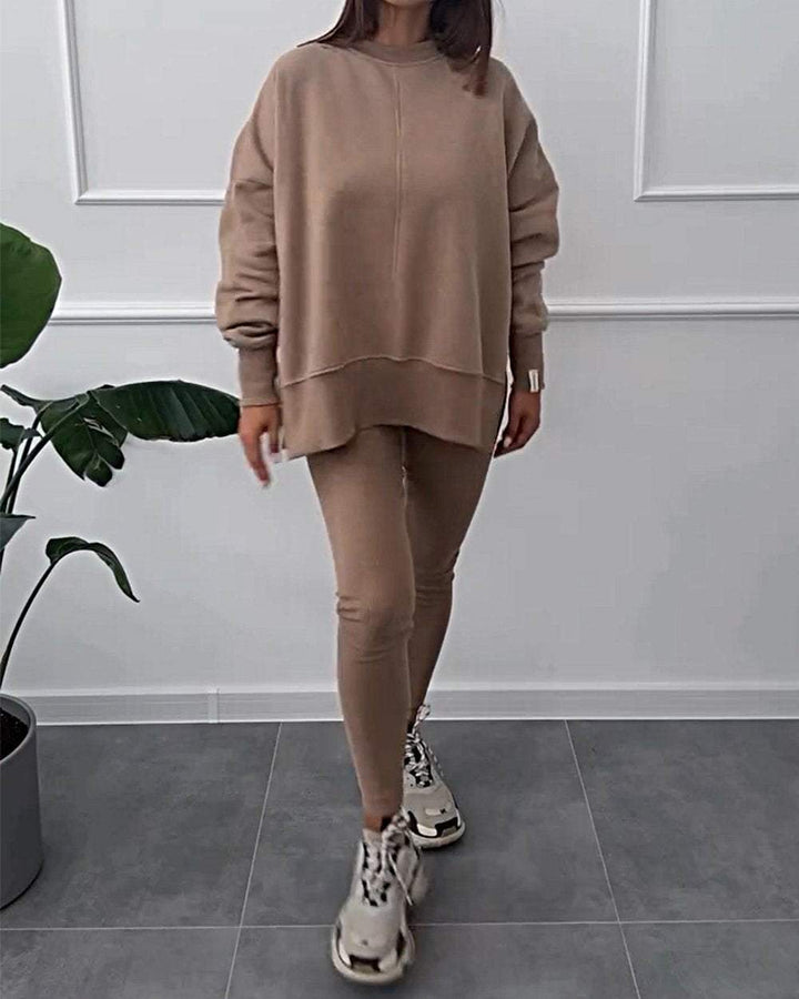 Frau in beigem Oversize-Sweatshirt und Leggings, modisch, lässig, Indoor, Pflanzenhintergrund.
