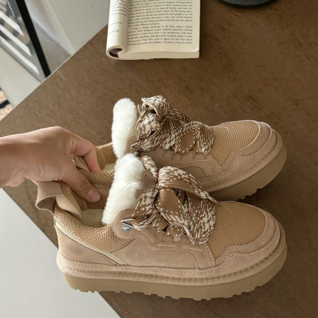 Beige Damen-Winterschuhe mit Fellfutter und gemusterten Schnürsenkeln auf Holztisch.