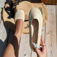 Beige Damen-Ballerinas aus Strickstoff, flach, mit Perlenring, auf Holzterrasse.