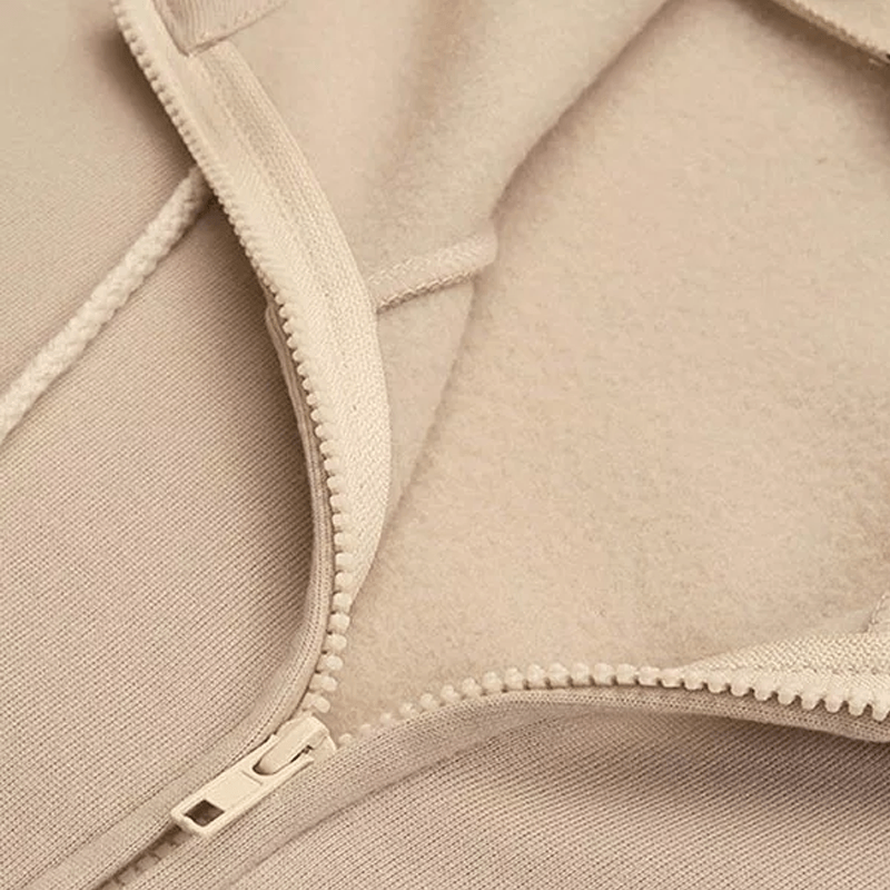 Beiger Fleece-Reißverschluss, Nahaufnahme, weiches Material, Textilstruktur, Mode-Detail.