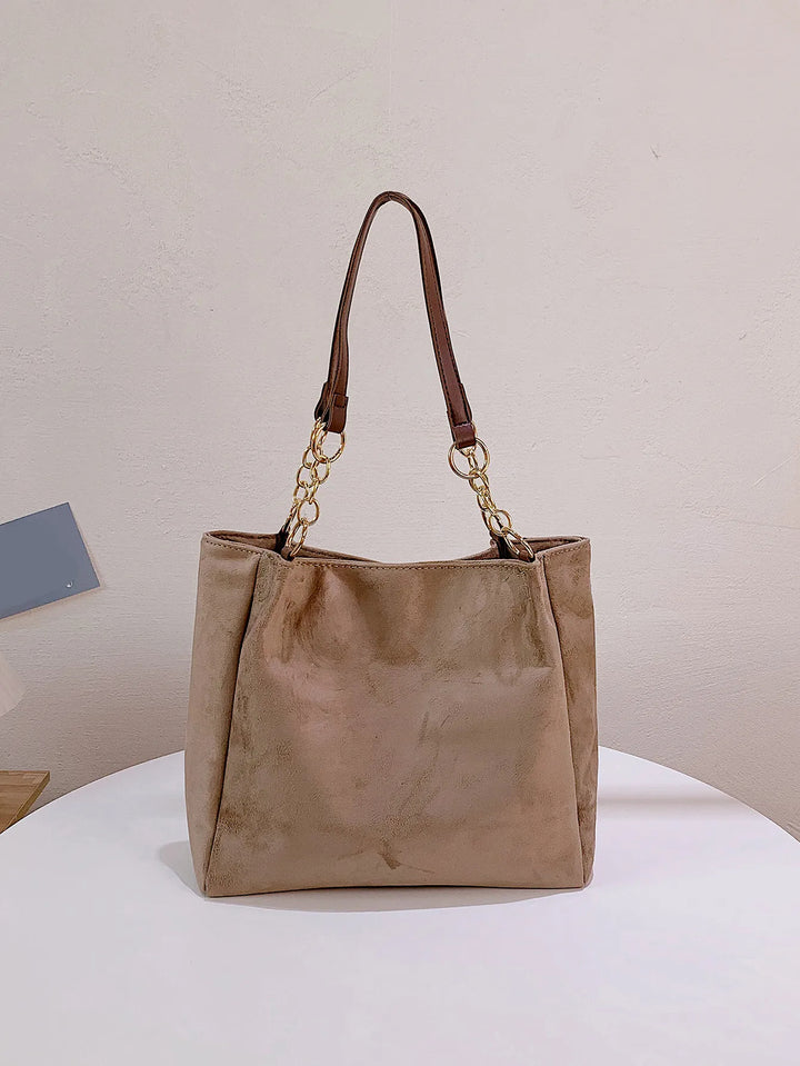 Beige Damenhandtasche aus Wildleder mit Kettenriemen, elegant und modisch.