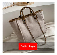 Beige Damenhandtasche aus Leinen mit braunen Ledergriffen und Kettendetail.