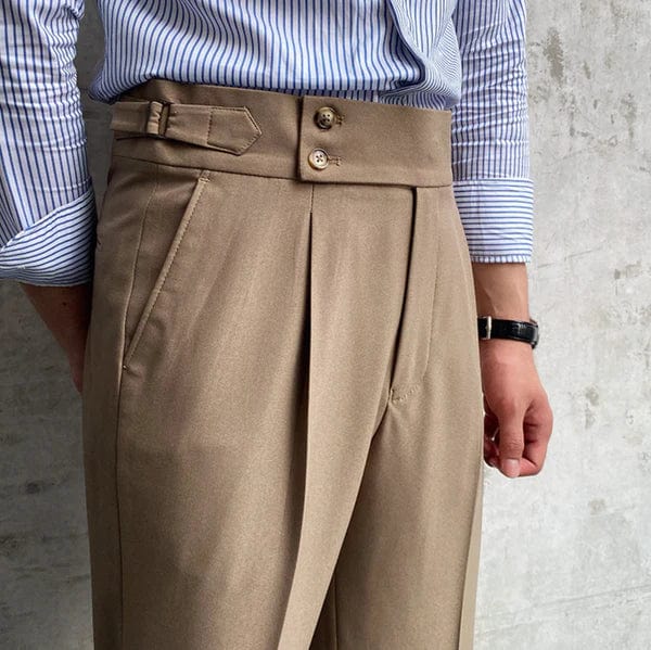 Beige Herrenhose mit hoher Taille, Bundfalten und Knöpfen, getragen mit gestreiftem Hemd.