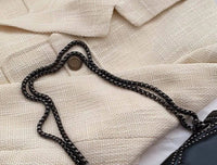 Beige Wollmantel mit schwarzer Kettentasche, elegante Damenmode, Herbst-Winter-Outfit.