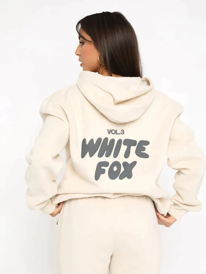 Frau in cremefarbenem Hoodie mit "White Fox" Aufdruck, lässige Mode, Streetwear, Rückansicht.