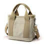 Beige Canvas-Handtasche mit Schulterriemen, modisch, robust, ideal für Alltag und Reisen.