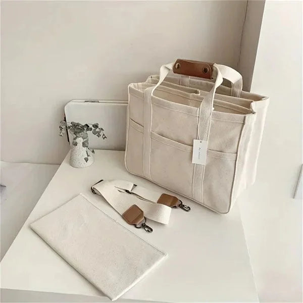 Beige Canvas-Tasche mit Tragegriffen, abnehmbarem Schultergurt, ideal für Alltag und Reisen.