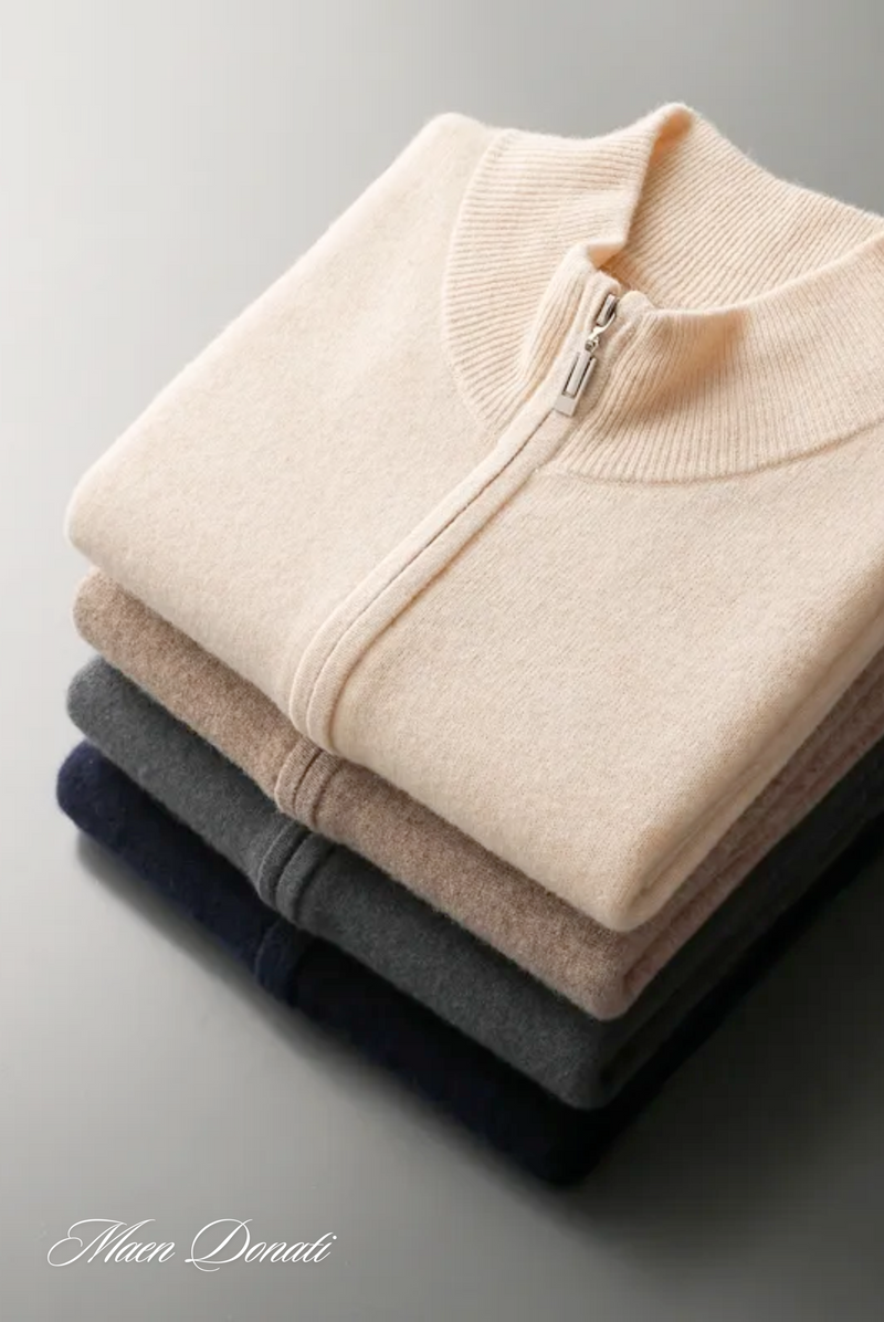 Beige Strickjacke mit Reißverschluss, gestapelt auf grauen, braunen und dunkelblauen Pullovern.