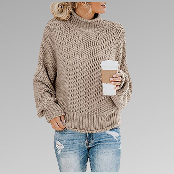 Frau in beigem Strickpullover mit Kaffeebecher, lässige Mode, Herbstoutfit, grauer Hintergrund.