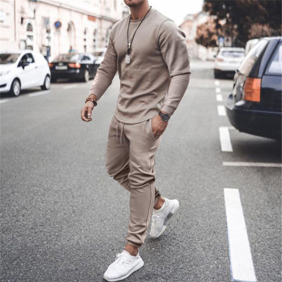 Mann in beigem Trainingsanzug und weißen Sneakers auf Straße, modische Freizeitkleidung.