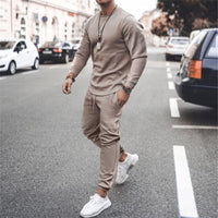 Mann in beigem Trainingsanzug und weißen Sneakers auf Straße, modische Freizeitkleidung.