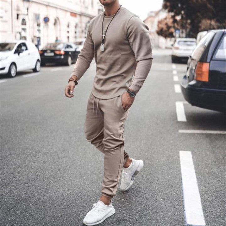 Mann in beigem Trainingsanzug und weißen Sneakers auf Straße, modische Freizeitkleidung.