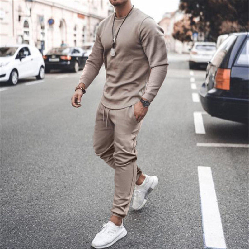 Mann in beigem Trainingsanzug und weißen Sneakers auf Straße, modische Freizeitkleidung.