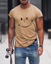 Mann in beigem T-Shirt mit Smiley-Design, Jeans, Skateboard, urbaner Hintergrund.