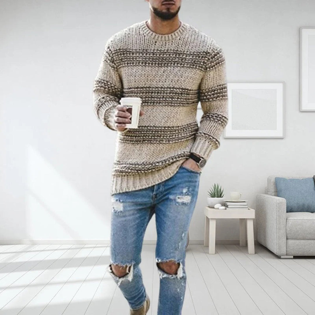 Mann in beige gestreiftem Strickpullover, zerrissene Jeans, hält Kaffeetasse, modernes Wohnzimmer.