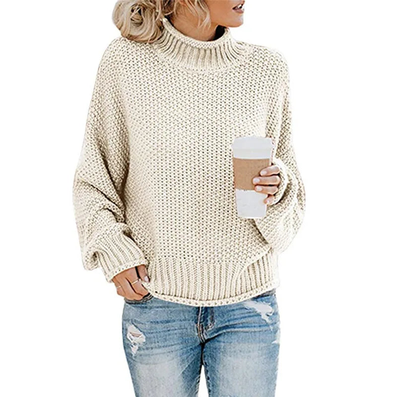 Frau in cremefarbenem Strickpullover mit Kaffeebecher und zerrissenen Jeans.