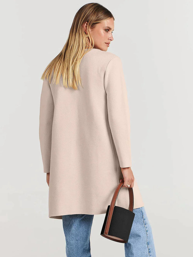 Frau in beigem Mantel, blaue Jeans, schwarze Handtasche, Mode, Damenbekleidung, Rückansicht.