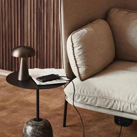 Beigefarbenes Sofa mit Kissen, schwarzer Beistelltisch, moderne Lampe, Smartphone, Notizbuch.