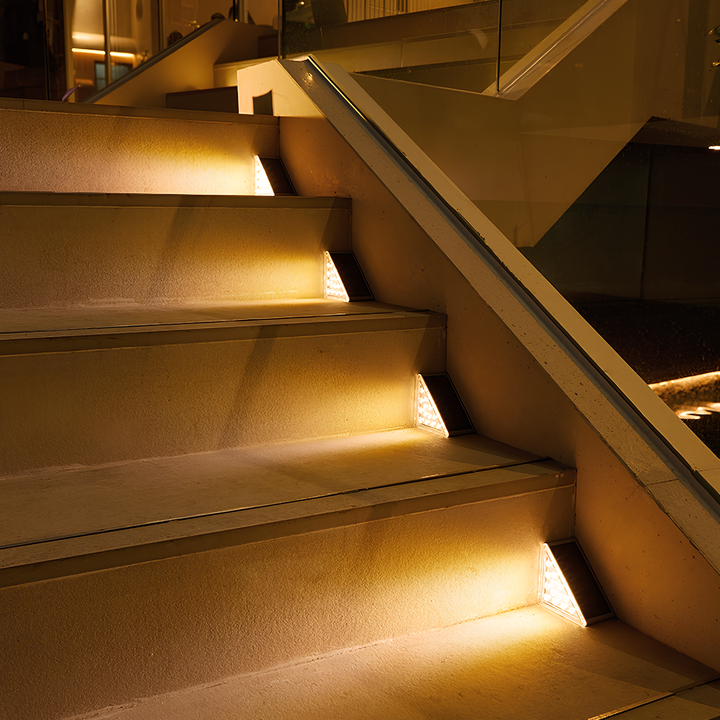 Beleuchtete Treppe mit LED-Stufenlichtern, modernes Design, Glasgeländer, Innenarchitektur.