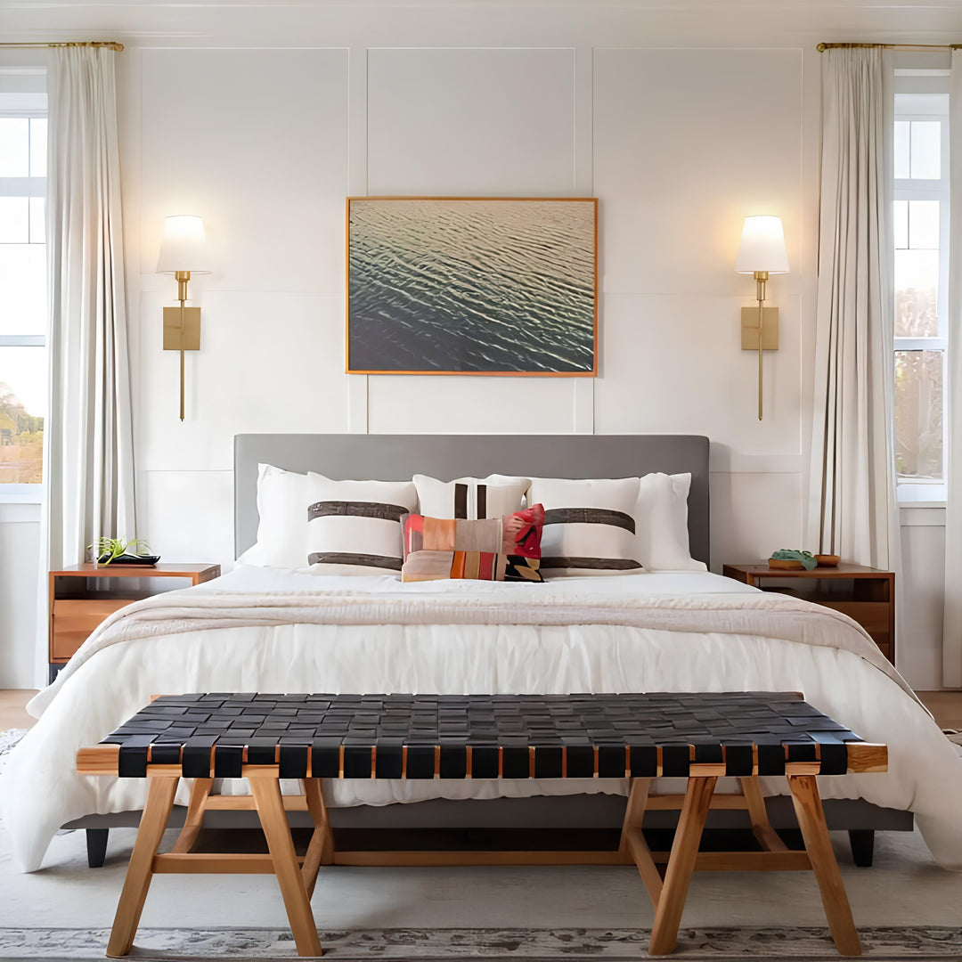 Modernes Schlafzimmer mit grauem Bett, Holznachttischen, Wandlampen und schwarzer Sitzbank.