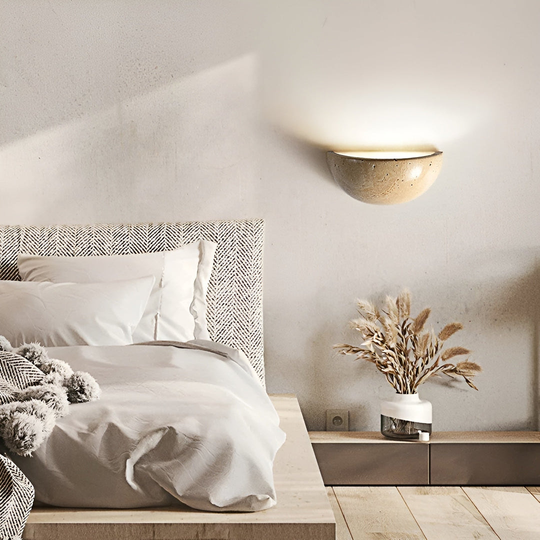 Bett mit gemustertem Kopfteil, weiße Bettwäsche, Wandlampe, Trockenblumen in Vase, modernes Schlafzimmer.
