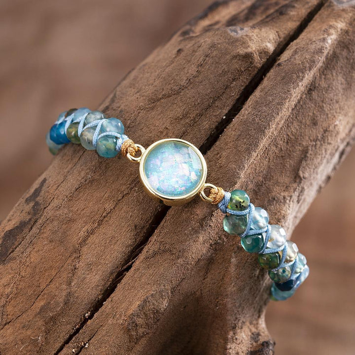 Blaues Opal-Armband, rund, geflochten, Yoga-Schmuck, Edelstein-Perlen, Balance, Holzuntergrund.