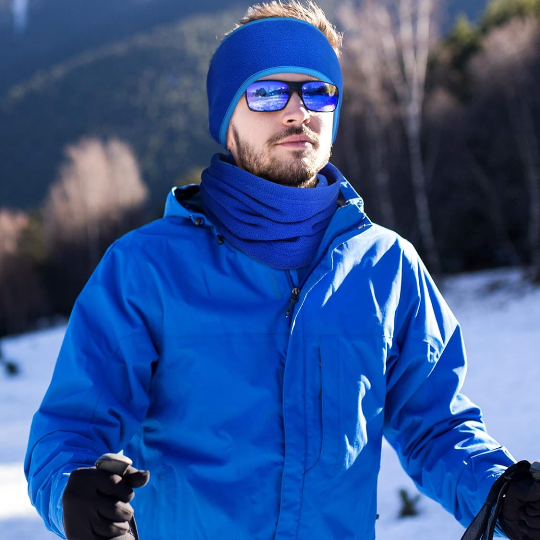 Mann in blauer Winterjacke, Mütze und Sonnenbrille beim Skifahren im Schnee, Wintermode.
