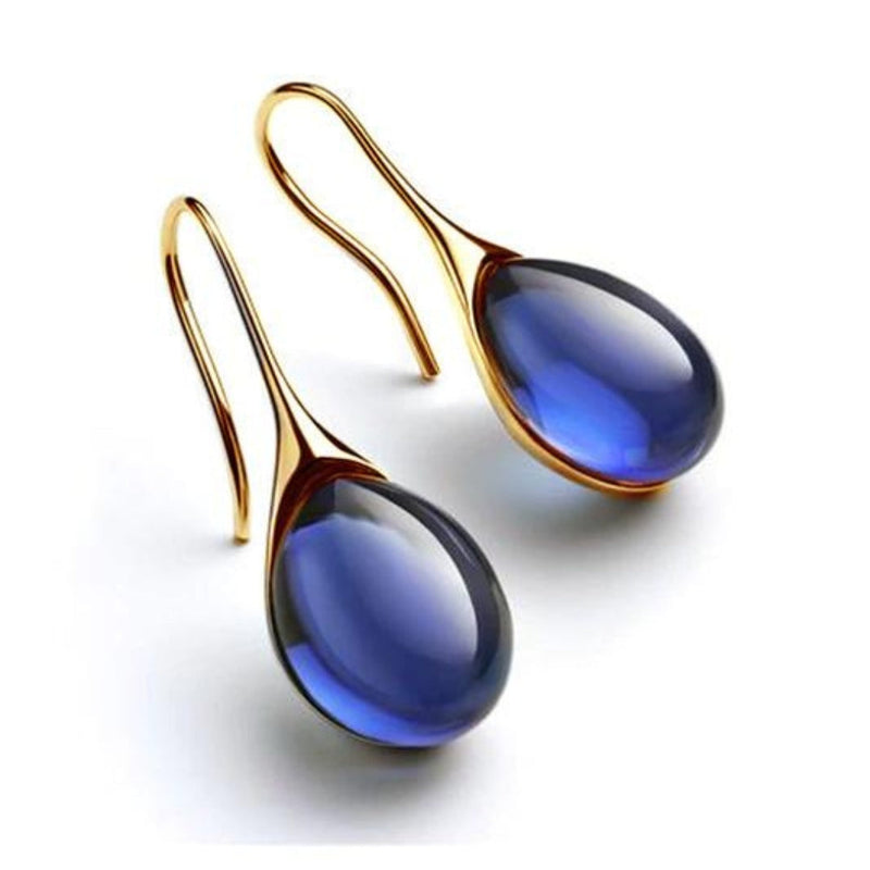 Goldene Ohrringe mit blauen Tropfenanhängern, eleganter Schmuck, modisches Accessoire.