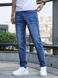 Mann in blauer Jeans und weißen Sneakers auf Balkon, urbaner Hintergrund.
