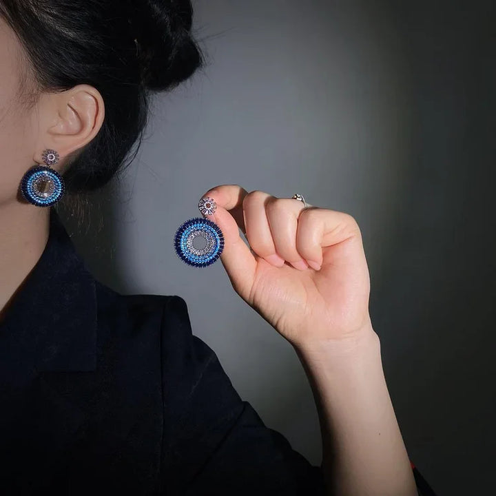 Blaue runde Ohrringe mit Strasssteinen, eleganter Schmuck, Damenaccessoire, Nahaufnahme.