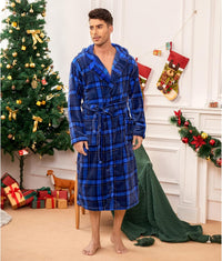 Mann im blauen karierten Bademantel vor Weihnachtsbaum und Geschenken.