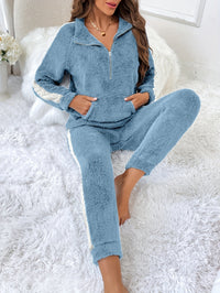 Frau in blauem Fleece-Trainingsanzug auf weißem Teppich, gemütliche Freizeitkleidung.