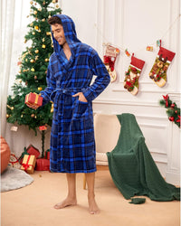 Mann im blauen karierten Bademantel vor Weihnachtsbaum, hält Geschenk, festliche Dekoration.