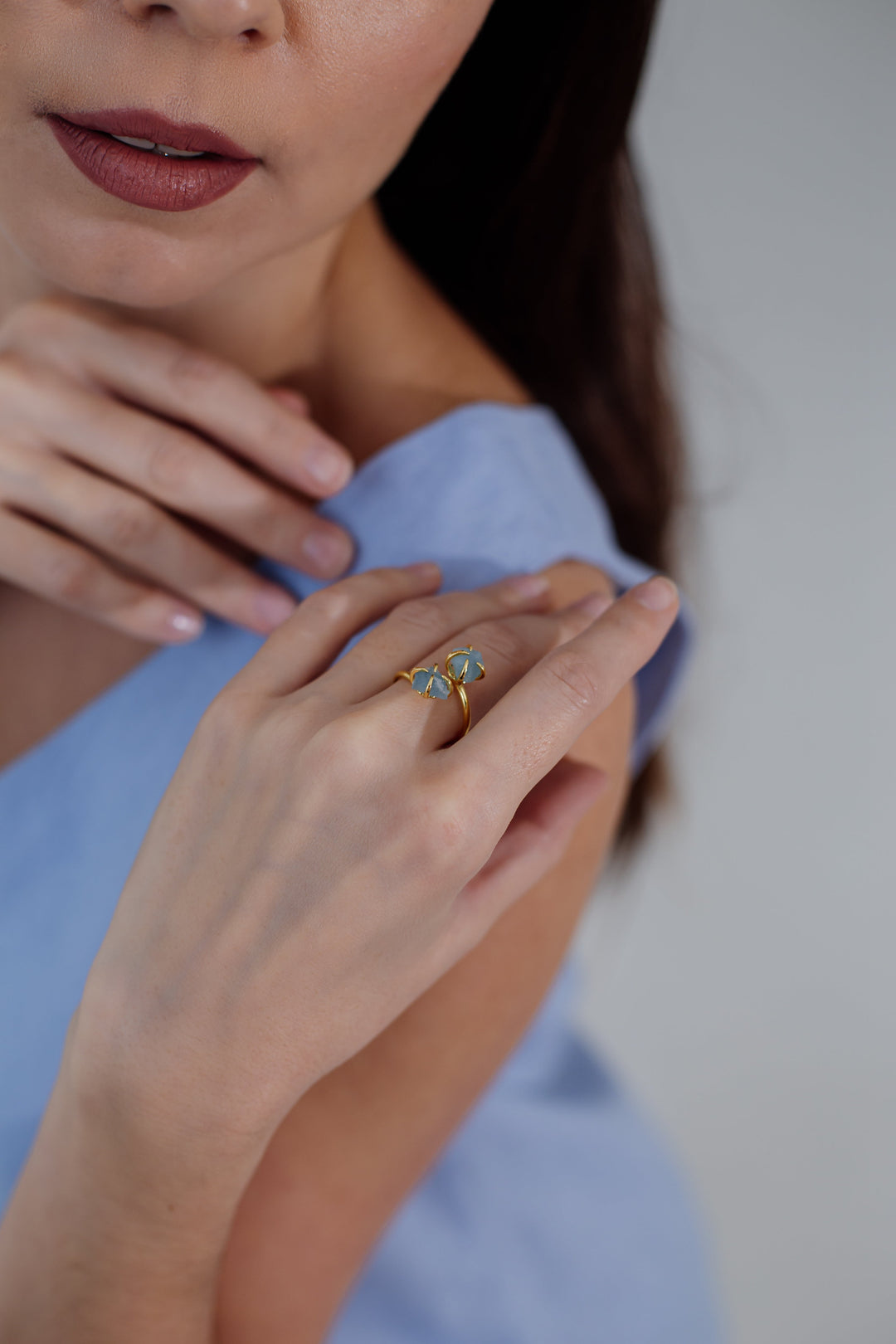 Frau mit blauem Kleid trägt goldenen Ring mit blauem Stein, Nahaufnahme, eleganter Schmuck.