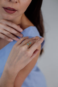 Frau mit blauem Kleid trägt goldenen Ring mit blauem Stein, Nahaufnahme, eleganter Schmuck.