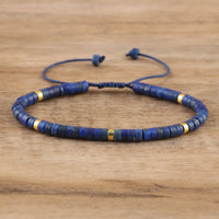 Blaues Lapis-Lazuli-Armband mit goldenen Akzenten, verstellbar, auf Holzoberfläche.