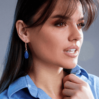 Frau mit blauen Ohrringen, blaues Hemd, braune Haare, Nahaufnahme, Modeaccessoire.