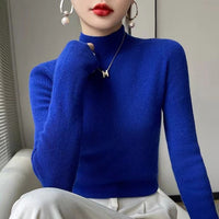 Frau in blauem Rollkragenpullover, Perlenohrringe, roter Lippenstift, eleganter Look.