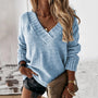 Frau in hellblauem Strickpullover, schwarze Shorts, braune Tasche, modischer Look.