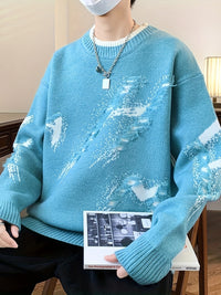 Person in blauem Strickpullover mit abstraktem Muster, hält ein Buch, modisch, lässiger Stil.