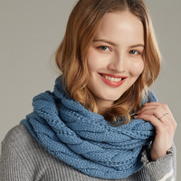 Frau mit blauem Strickschal, lächelnd, grauer Pullover, modisches Winteraccessoire.