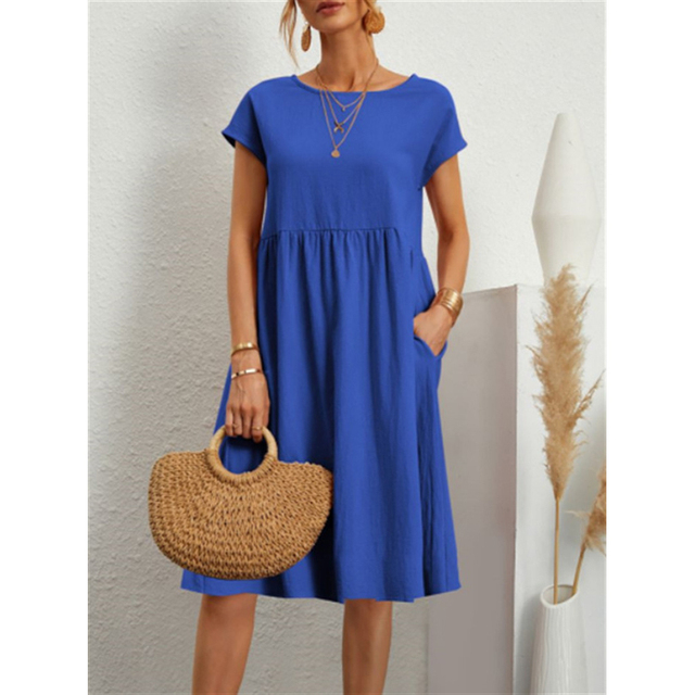 Frau in blauem Baumwollkleid, A-Linie, mit Strohtasche, Sommermode, Boho-Stil.