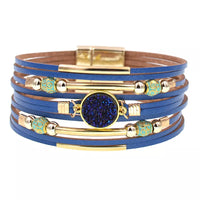 Blaues Lederarmband mit goldenen Akzenten und blauem Kristall, modisches Schmuckstück.